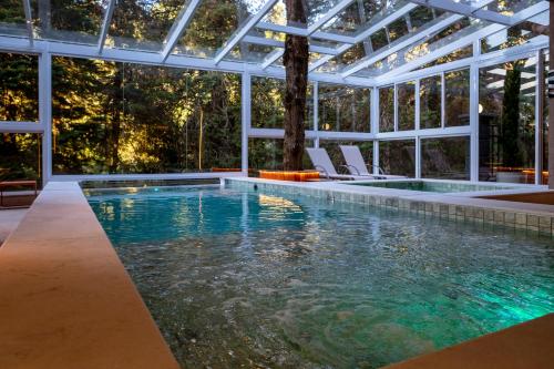 an infinity pool with chairs and a glass house at Champet Boutique Hotel in Campos do Jordão