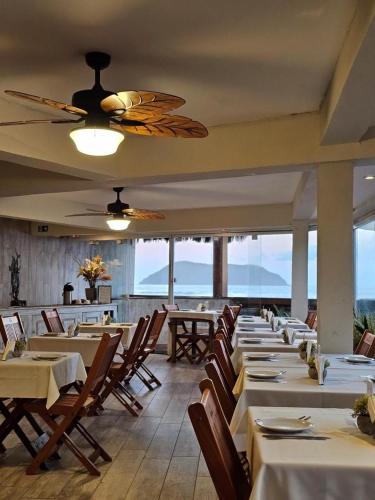 a dining room with tables and chairs and windows at Juquehy La Plage Hotel in Juquei