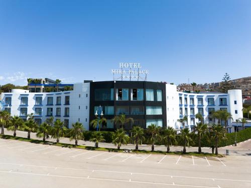 a building with palm trees in front of a parking lot at Mira Palace Hotel in Al Hoceïma