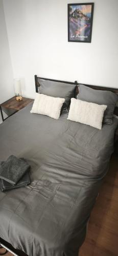 a large gray bed with two pillows on it at Le Ventoux - Studio Climatisé - Provence in Aubignan