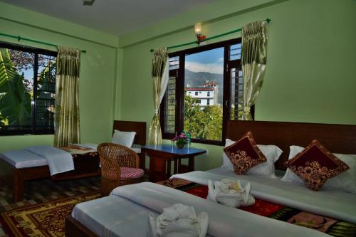 1 dormitorio con 2 camas, mesa y ventanas en Hotel Mandala, en Pokhara
