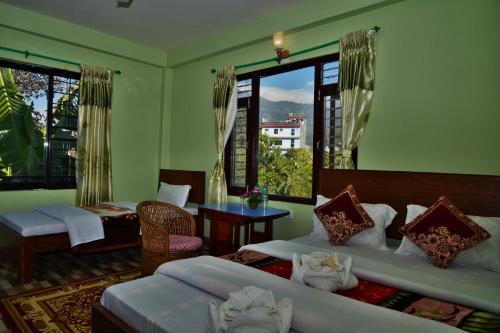a bedroom with two beds and a table and windows at Hotel Mandala in Pokhara
