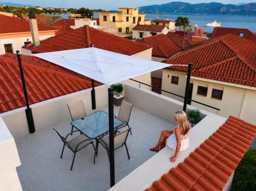 a woman sitting on a balcony with a table and an umbrella at Incanto Luxury Suites in Nafpaktos