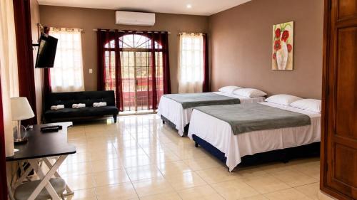 a hotel room with two beds and a television at Suite Familiar Afrodita - Centro Histórico in Comayagua