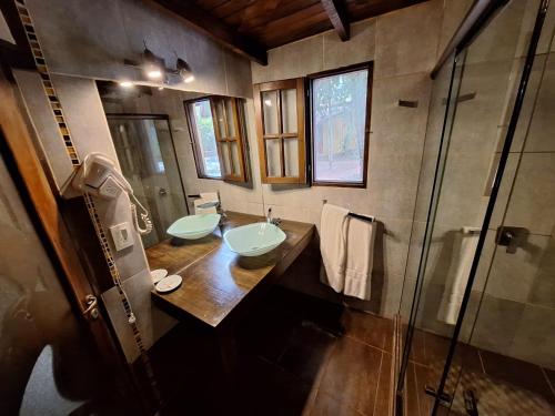 a bathroom with two sinks and a glass shower at La Locanda Art & Taste Retreat in Puerto Iguazú