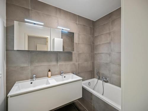 a bathroom with a sink and a tub and a mirror at B City Complex - 0302 in Blankenberge