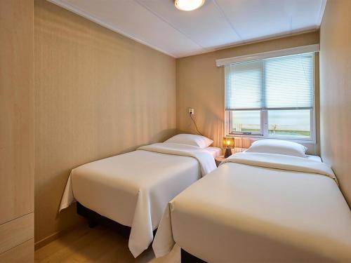 three beds in a room with a window at t Kaatsheuveltje 9 in Kaatsheuvel
