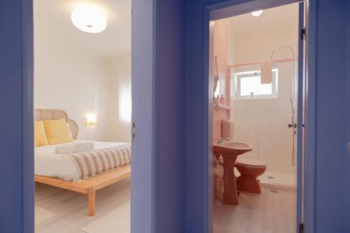 a bedroom with a bed and a bathroom with a sink at Feel Nazaré - Ocean Villa in Nazaré