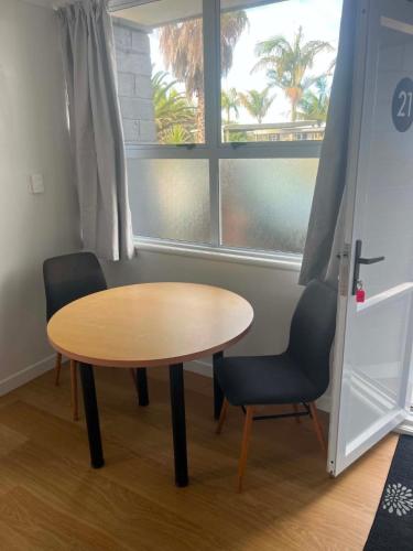 ein Tisch und zwei Stühle in einem Zimmer mit Fenster in der Unterkunft The Awanui Hotel in Awanui