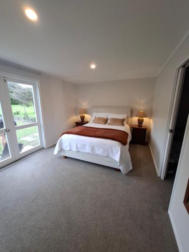 a bedroom with a large bed and a large window at Among The Tuii in Katikati