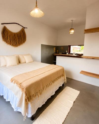 a bedroom with a white bed with a brown blanket at Lá na Chay Caraíva Refúgio tranquilo & experiência local in Caraíva