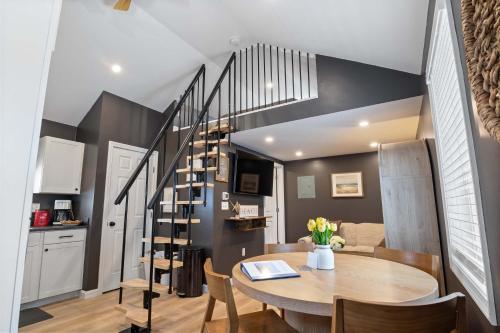 a dining room with a table and a spiral staircase at Coral Cottage - Tiny Home at Hampton Beach in Hampton