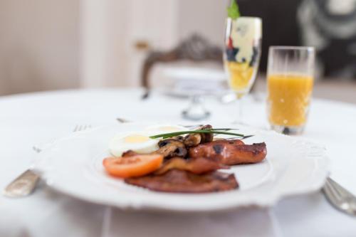 ein Teller mit Lebensmitteln auf einem Tisch mit einem Glas Orangensaft in der Unterkunft The Kingsman boutique Hotel in Burgersdorp