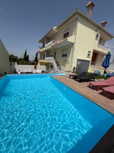 a large blue swimming pool in front of a house at Moradia com escada, Jardim e piscina, 3Kms Praia in Almada
