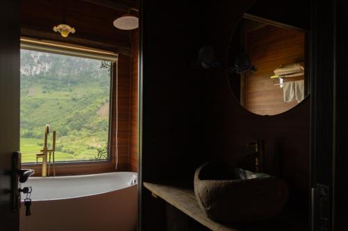 a bathroom with a tub and a window and a sink at Bamboo Hill Resort in Hữu Lũng