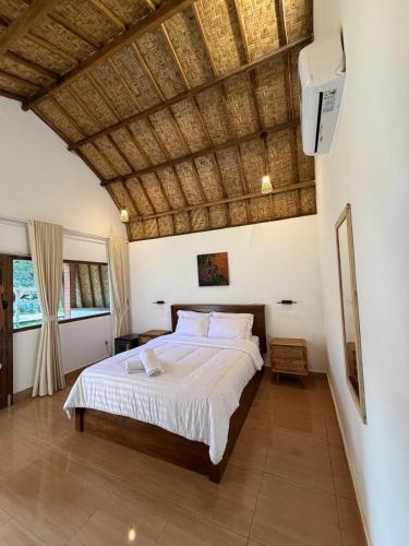 a bedroom with a large bed with a wooden ceiling at Jati Rinjani Tetebatu in Tetebatu