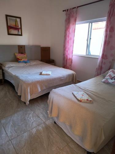 two beds in a room with a window at Recanto dos Braga in Saquarema