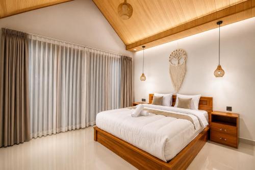 a bedroom with a large bed and a large window at The Tamarin Villas in Nusa Penida