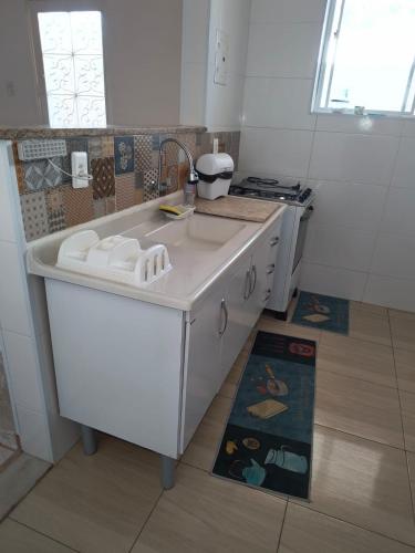 a white kitchen with a sink and a stove at Recanto dos Braga in Saquarema