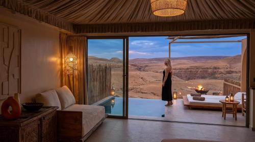 a woman standing in a living room with a view of the desert at Agafay Luxury camp in Marrakesh