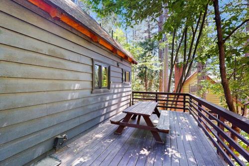 a wooden bench sitting on a deck next to a building at Wooded Comfort in Lake Arrowhead