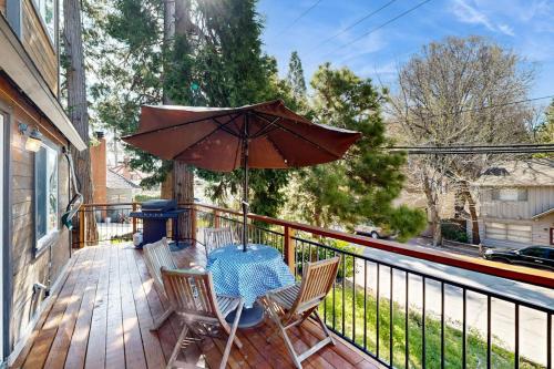 a table and chairs on a deck with an umbrella at Heliotrope Hideaway in Lake Arrowhead