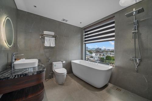a bathroom with a tub and a toilet and a sink at MAIA Boutique Hotel Da Nang in Danang