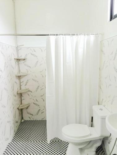 a bathroom with a toilet and a shower curtain at Veronica Palms in Pooc