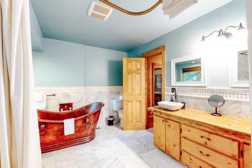 a bathroom with a wooden tub and a sink at Sky High Cabin in Crestline