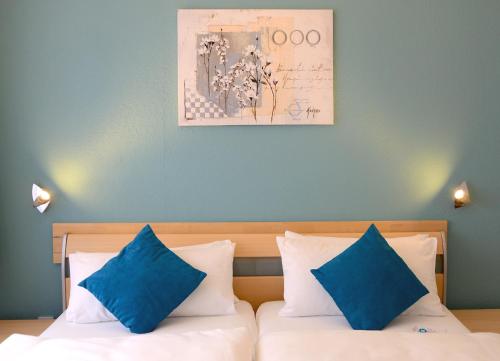 ein Schlafzimmer mit einem Bett mit zwei blauen Kissen in der Unterkunft Hotel Herrenhof in Lübeck