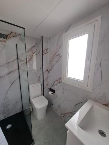 a bathroom with a toilet and a sink and a window at H Bella Mar Roses in Roses