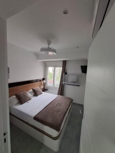 a bedroom with a bed with white sheets and a window at H Bella Mar Roses in Roses