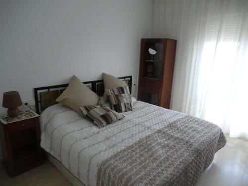 una camera da letto con letto, cuscini e finestra di Casas Holiday - Golf Willamartin a Villamartin