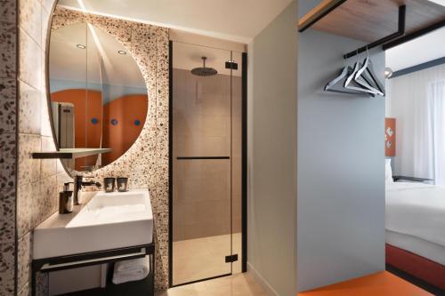 a bathroom with a sink and a mirror at Me and All Hotel Leipzig, by Hyatt in Leipzig