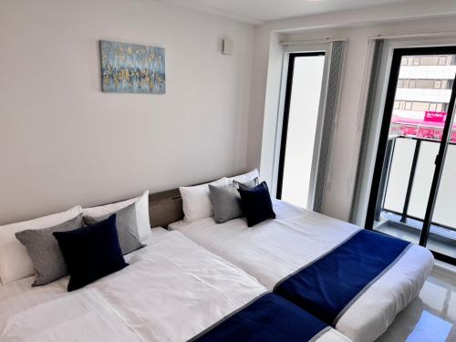 a large bed in a room with two windows at LIFEMENTGLANZ HOTEL Enomachi in Hiroshima