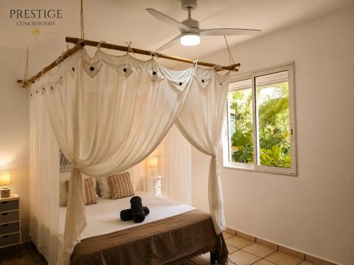a bedroom with a canopy bed with a window at Petit Havre de Paix BIS - Piscine et plage à pied in Le Gosier