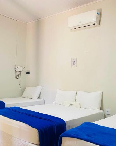 two beds in a room with blue sheets at Chalé Brisa da Lagoa in Icaraí