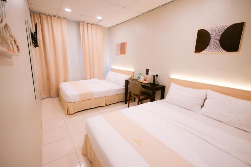 a hotel room with two beds and a desk at Rovers Hotel Kubang Kerian in Kota Bharu