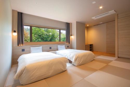 two beds in a bedroom with a window at TAOYA Gero in Gero