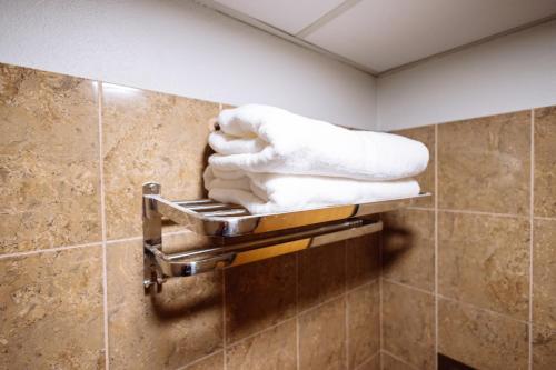 a pile of towels on a towel rack in a bathroom at Rovers Hotel Kubang Kerian in Kota Bharu