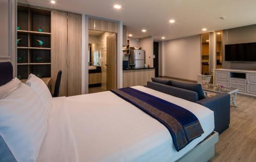 a bedroom with a large bed and a living room at Chaidee Mansion in Bangkok