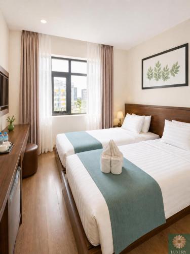a hotel room with two beds and a television at Corner Central Danang City Hotel in Danang