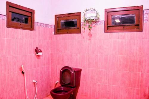 a pink bathroom with a toilet and two windows at Claasz Prime Lagoon in Katunayaka