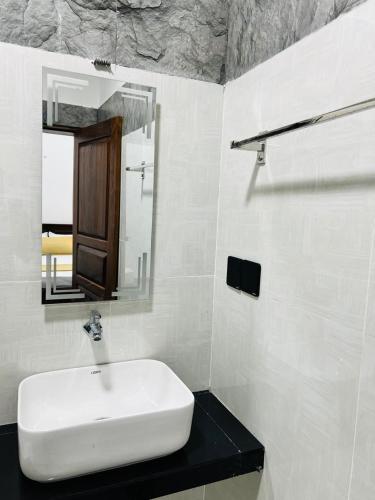 a white bathroom with a sink and a mirror at Luna Mara in Arugam Bay