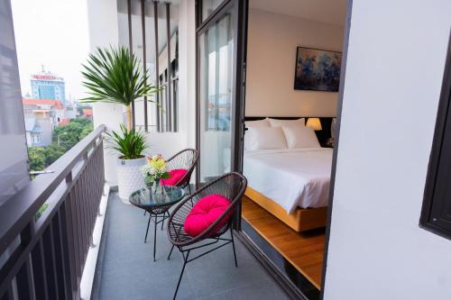 a balcony with a bed and chairs and a glass table at CELINA HOTEL Ninh Bình in Ninh Binh