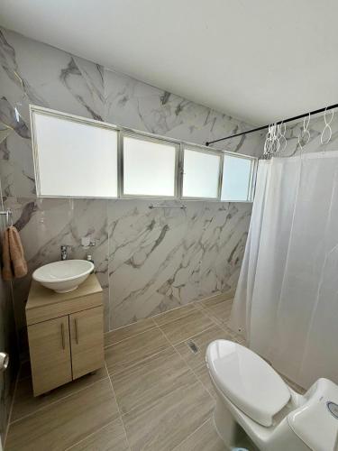 a bathroom with a white sink and a toilet at Hostal Beko in Cali