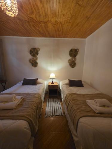 a room with two beds and a lamp on a table at Hostal Desert in San Pedro de Atacama