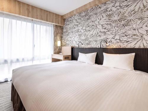 a bedroom with a large bed and a large window at Nishitetsu Resort Inn Naha in Naha