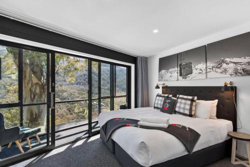 a bedroom with a large bed and large windows at Tyrola 11 in Thredbo