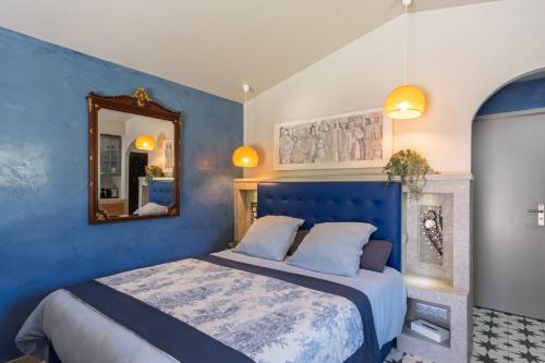 a blue bedroom with a bed and a mirror at Maisonnette climatisée in Aix-en-Provence